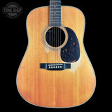A vintage-style acoustic guitar with a natural sunburst finish, black pickguard, and black bridge, shown against a solid black background with a Tone Shop watermark in the top left corner.