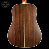 The back of an acoustic guitar made of rich dark brown wood with a single light-colored center stripe and white binding, shown against a solid black background.