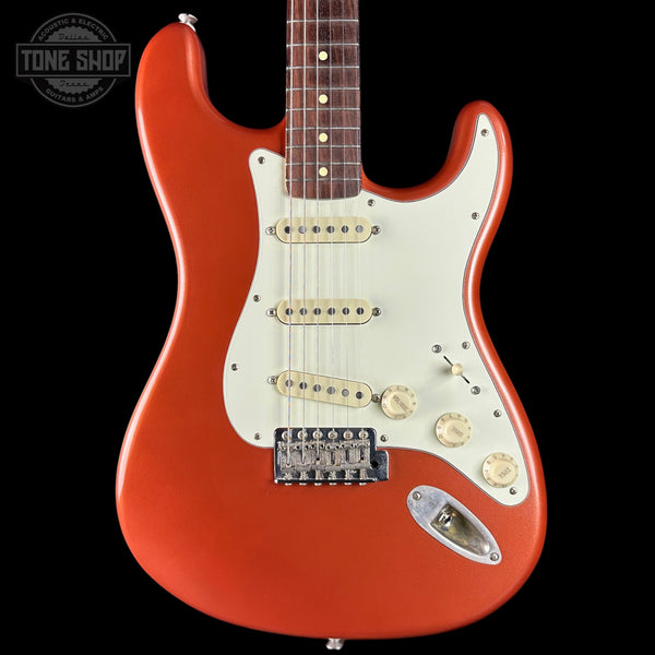 Red electric guitar with a white pickguard on a black background, featuring the Tone Shop logo.