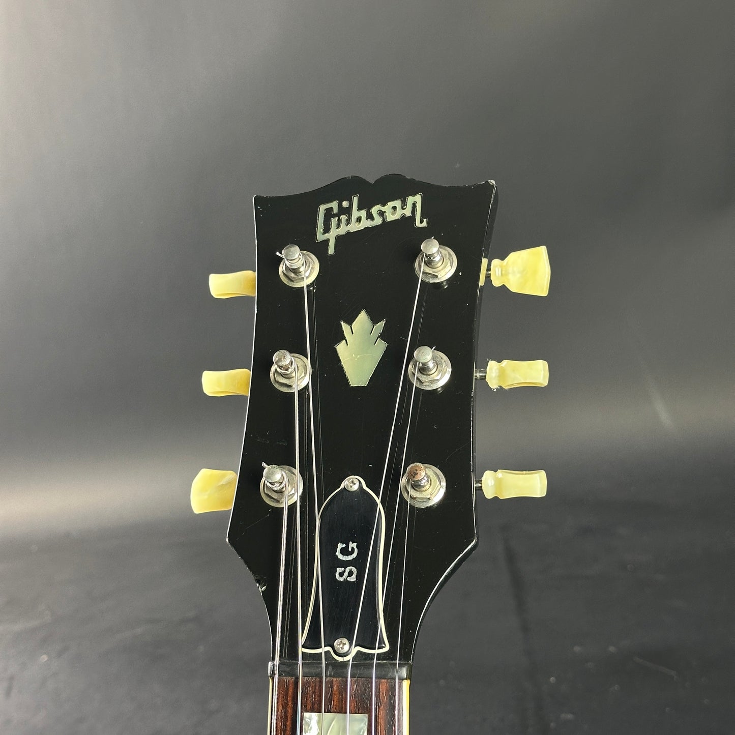 Gibson guitar headstock with tuning pegs on a dark background