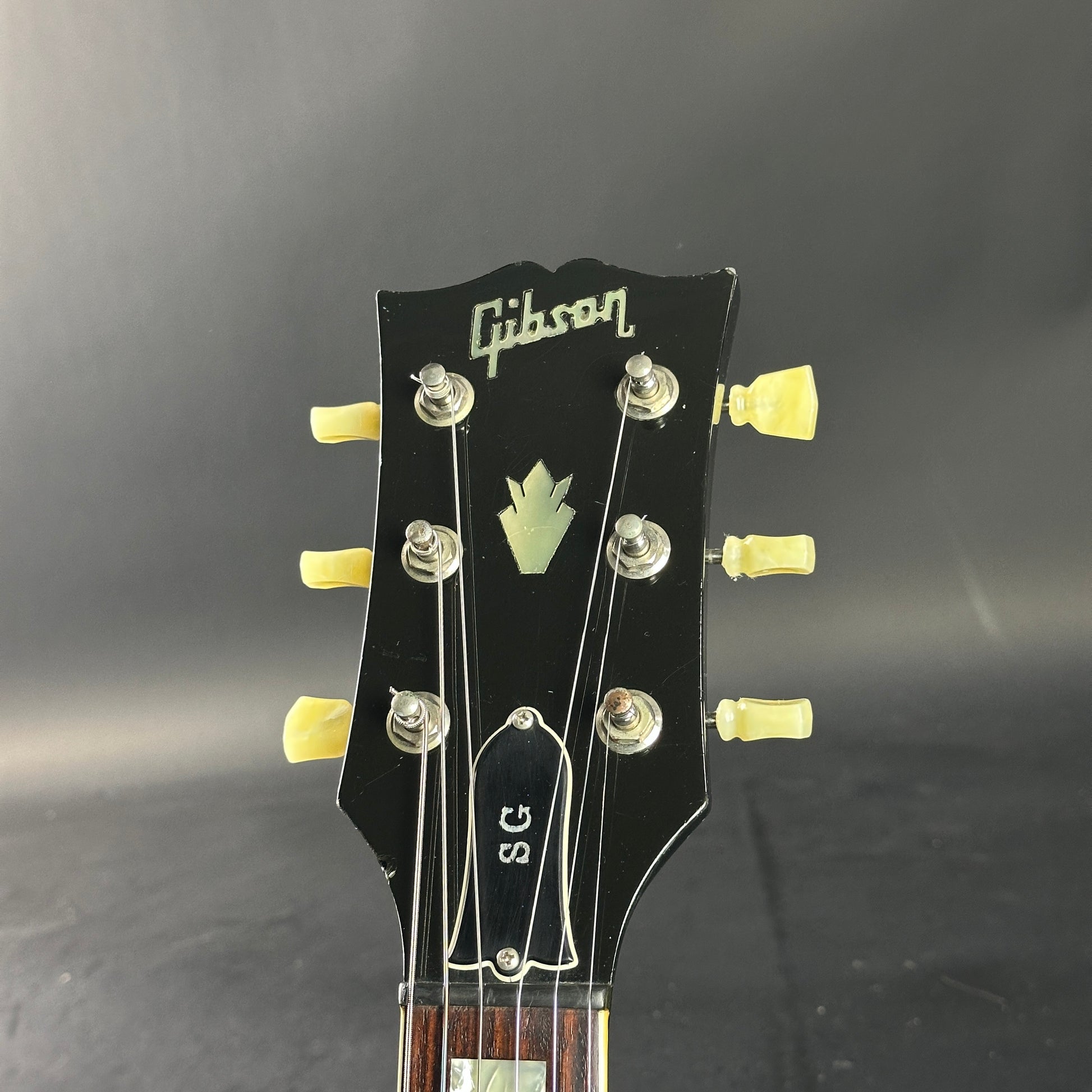 Gibson guitar headstock with tuning pegs on a dark background