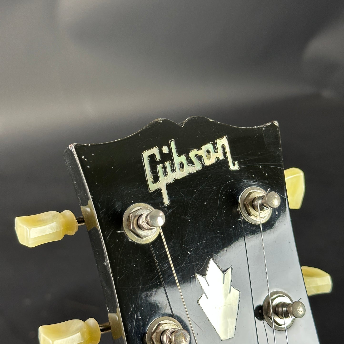 Gibson guitar headstock with tuning pegs on a dark background
