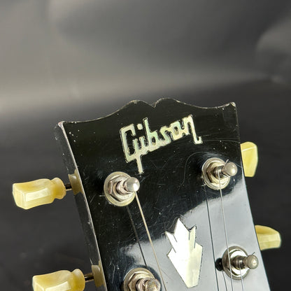 Gibson guitar headstock with tuning pegs on a dark background