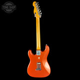 Orange electric guitar with a black background