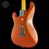 Orange electric guitar with a visible brand logo on a black background