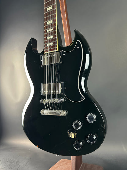 Black electric guitar on a reflective surface with a neutral background