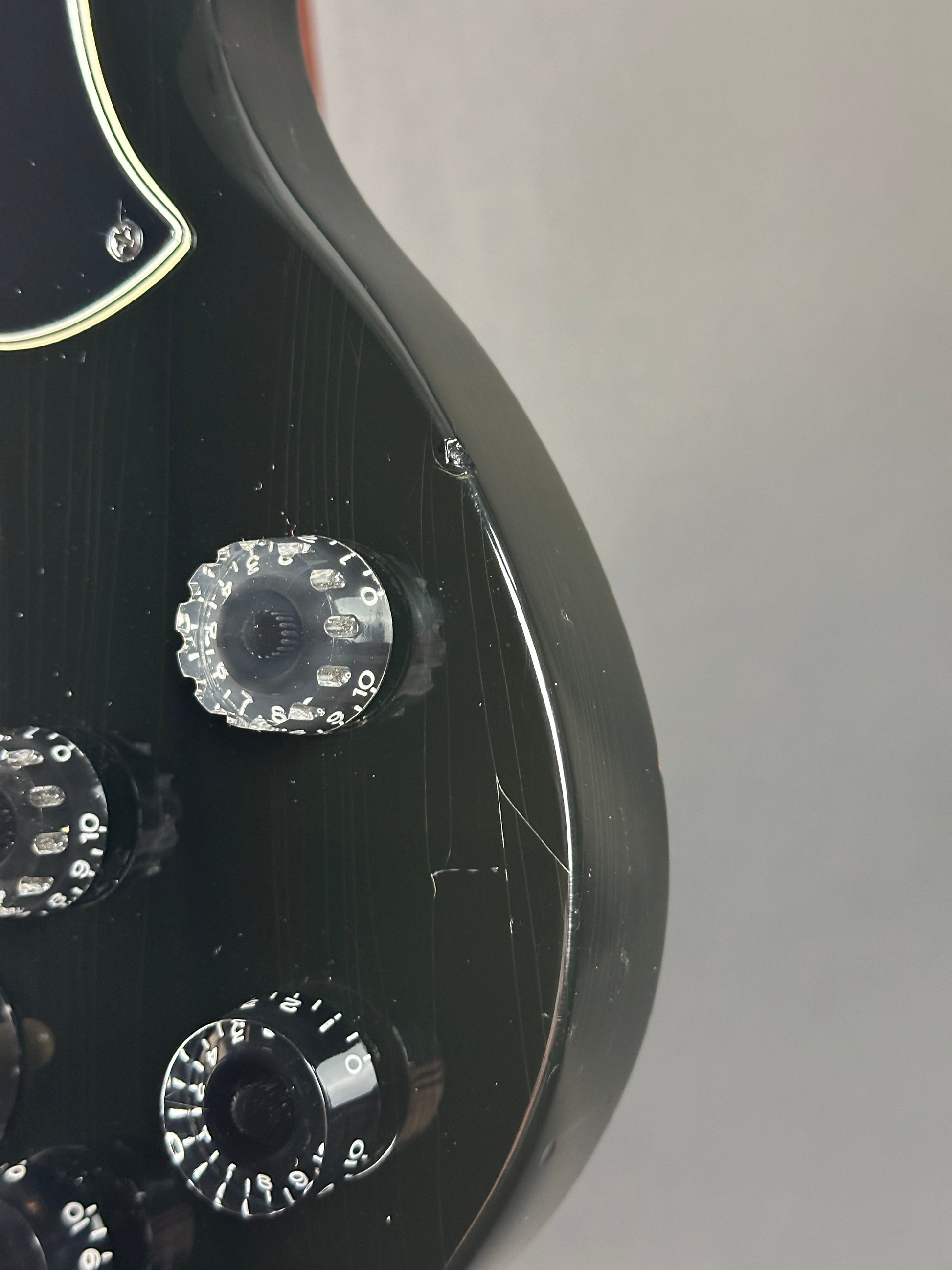 Close-up of a guitar's headstock with tuning pegs on a gray background