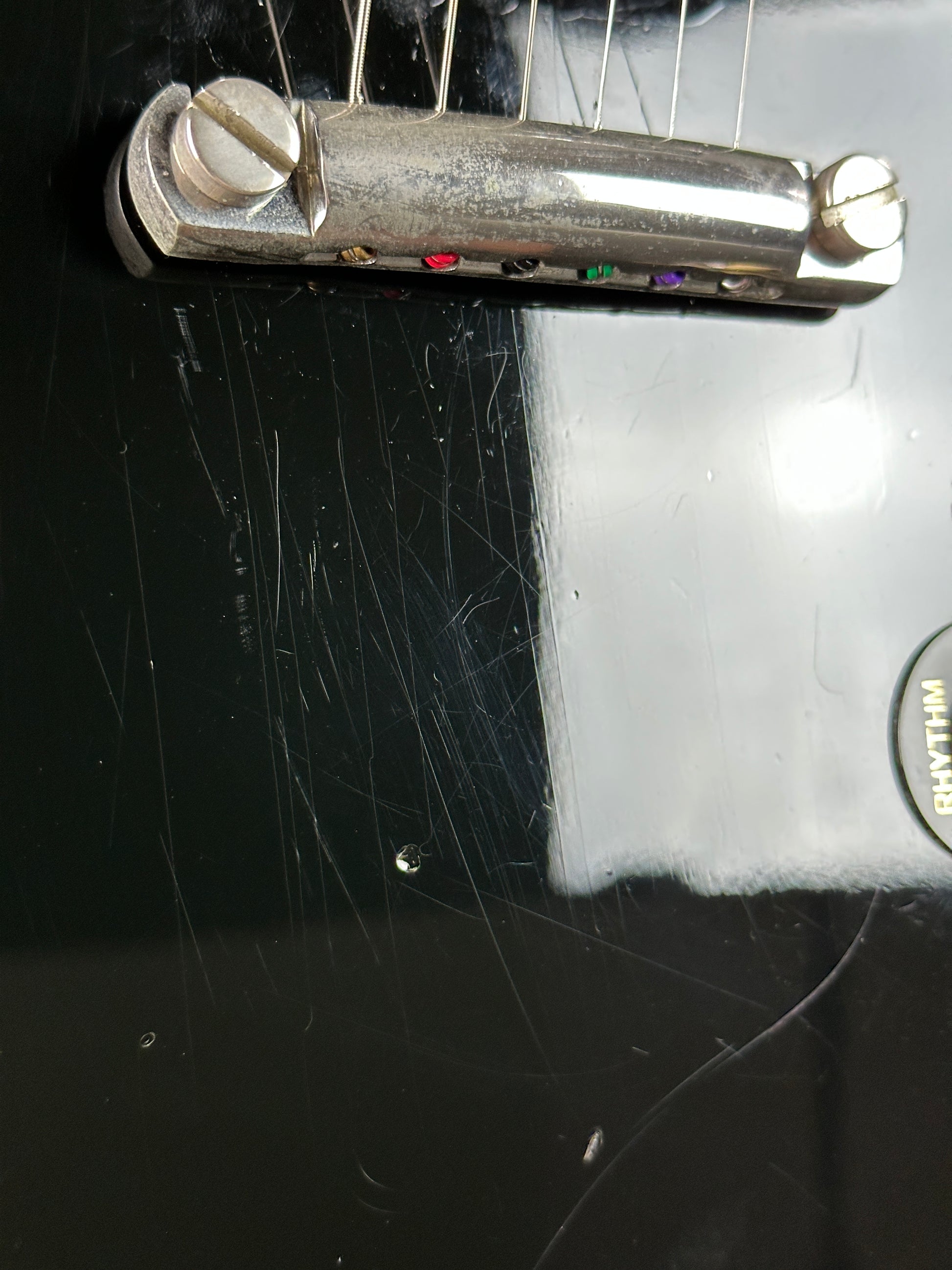 Close-up of a guitar's tuners on a black guitar body with visible wear.