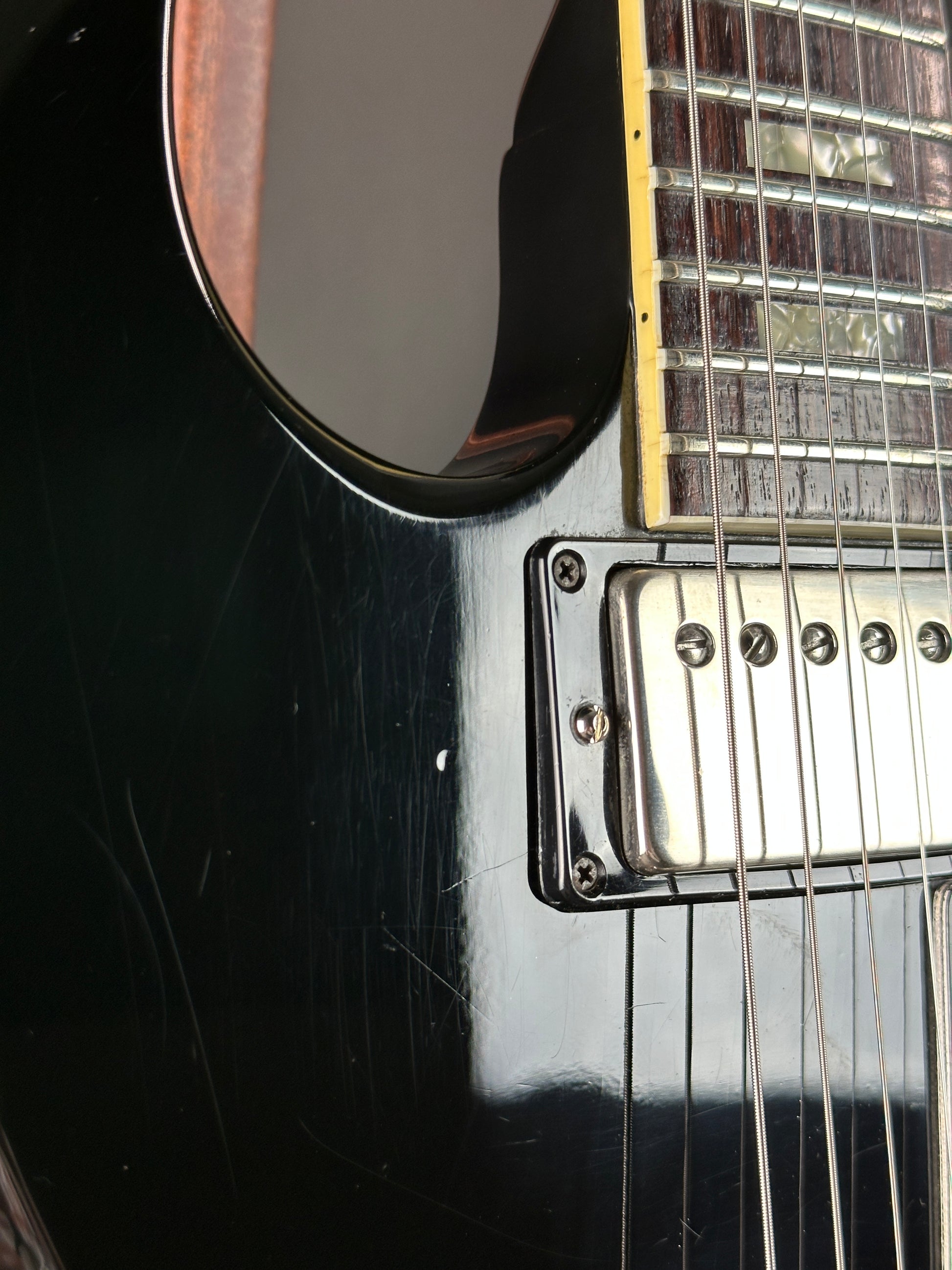Close-up of a black electric guitar with visible strings and body