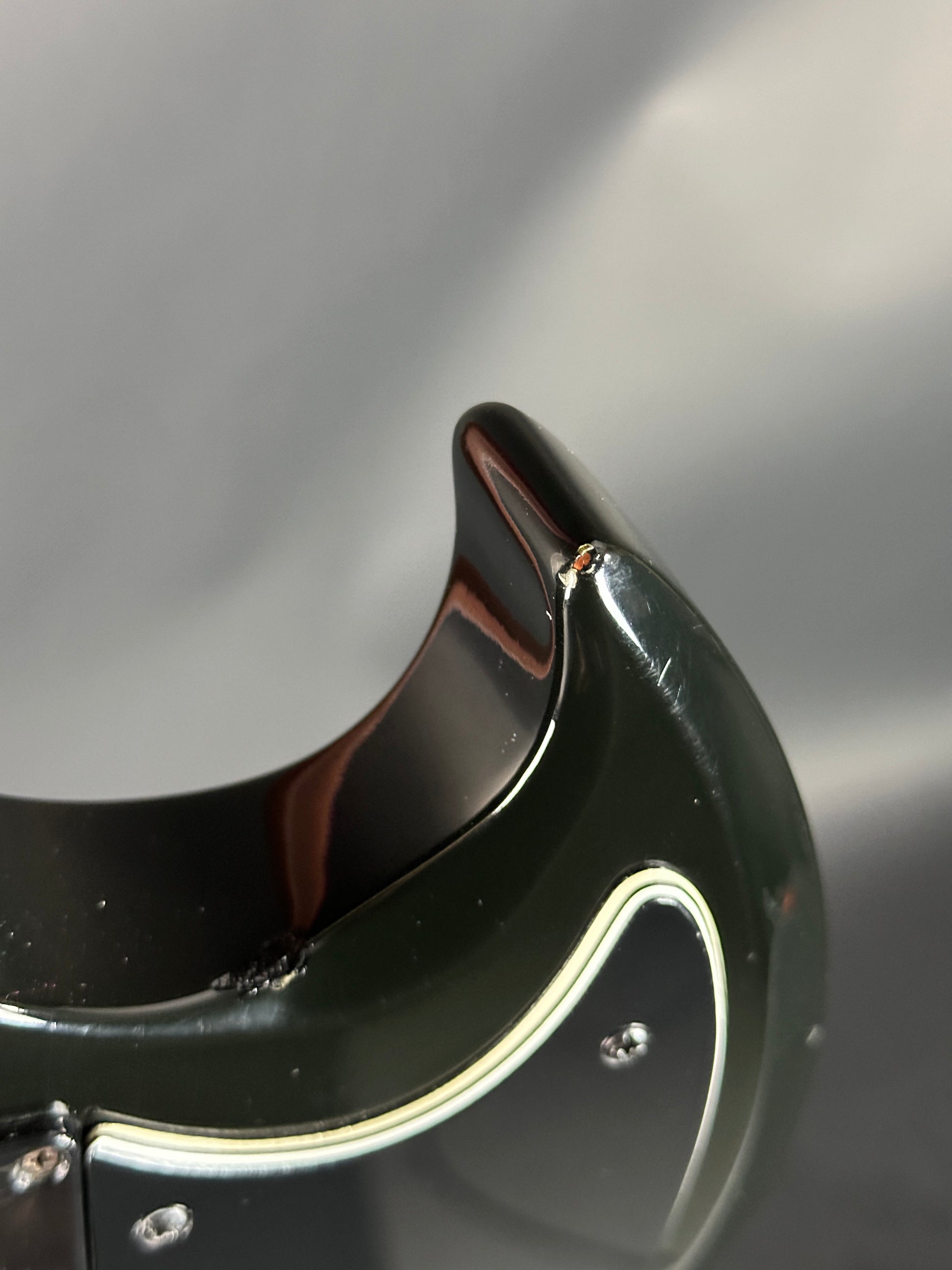 Close-up of a black and gold guitar pickguard with a blurred background