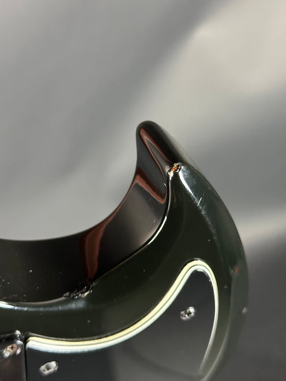 Close-up of a black and gold guitar pickguard with a blurred background