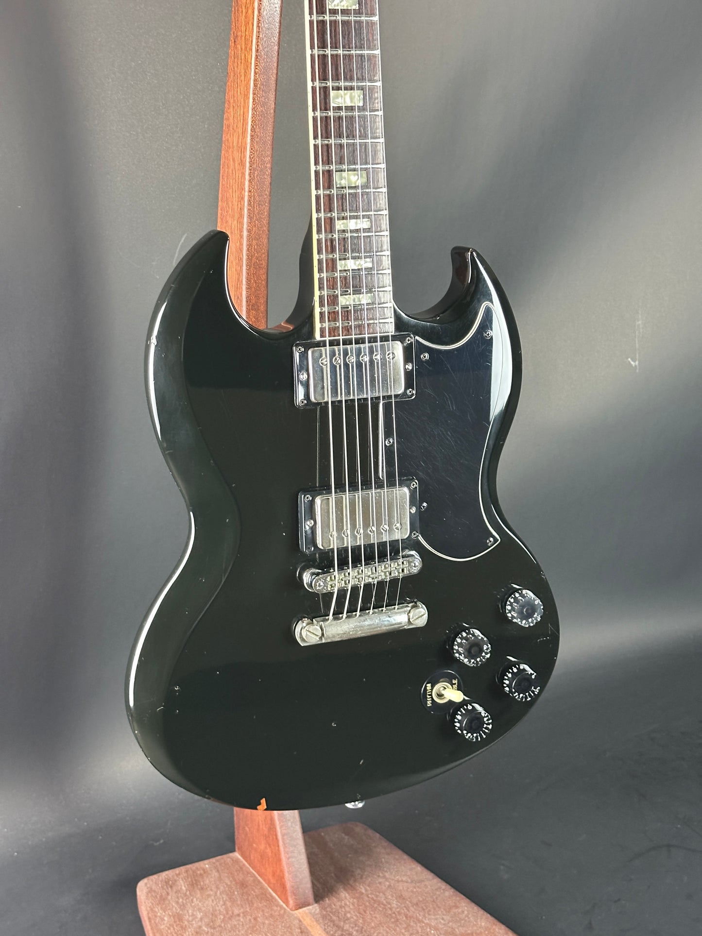 Black electric guitar with a wooden neck on a dark background