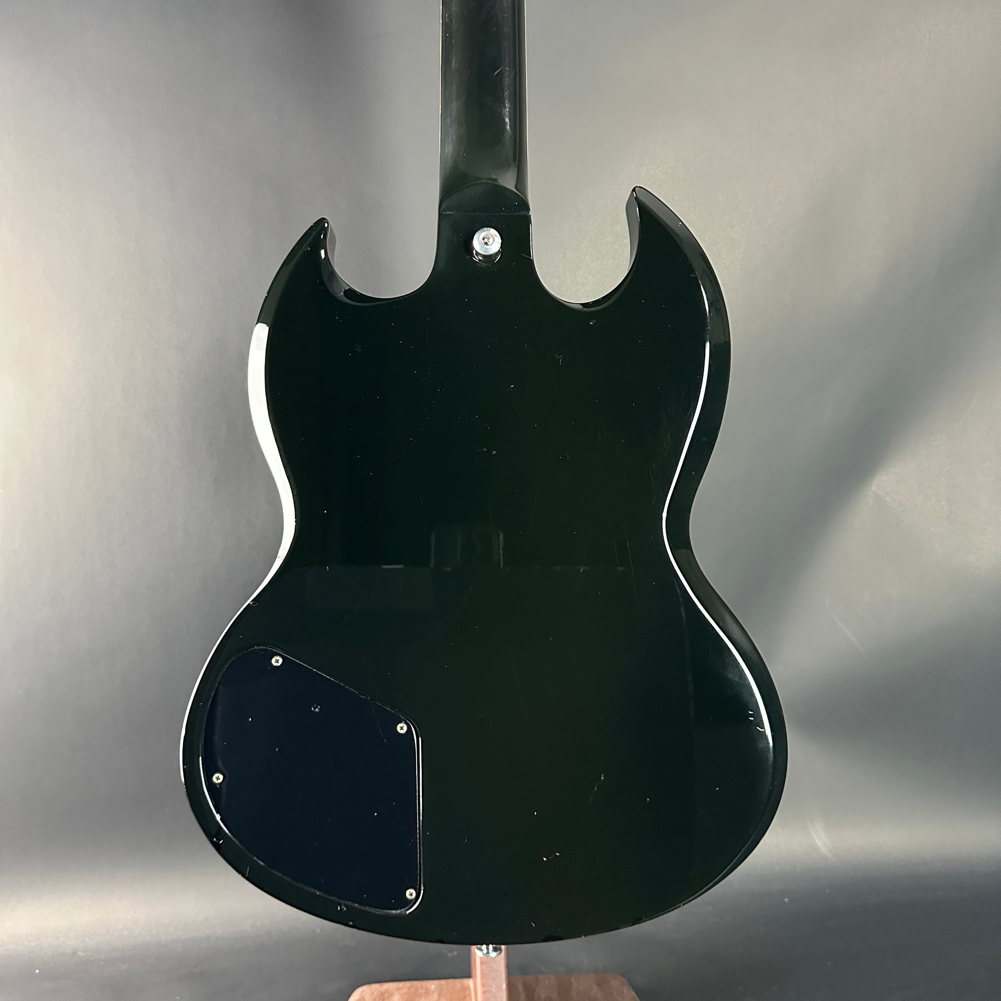 Black electric guitar body on a stand against a gray background