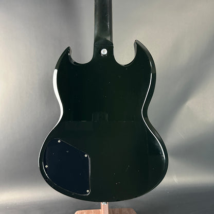 Black electric guitar body on a stand against a gray background