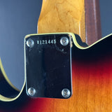 Close-up of the back of an electric guitar showing the black pickguard with silver screws, a sunburst finish, and part of the neck.