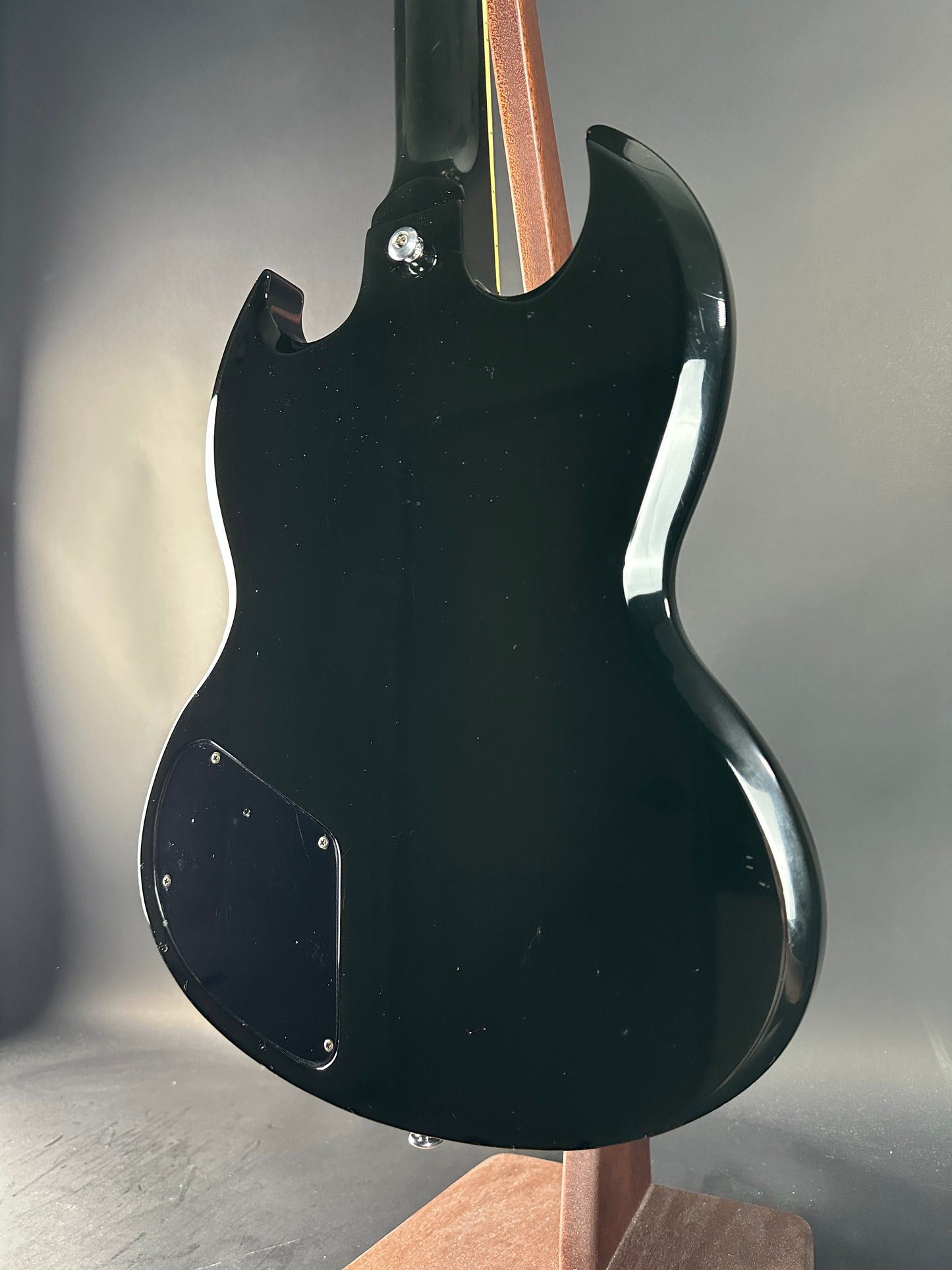 Close-up of a black electric guitar body on a gray background