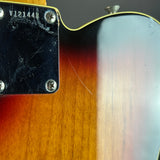 Close-up of the back of an electric guitar showing the sunburst finish, wood grain, and part of the black pickguard with silver screws.