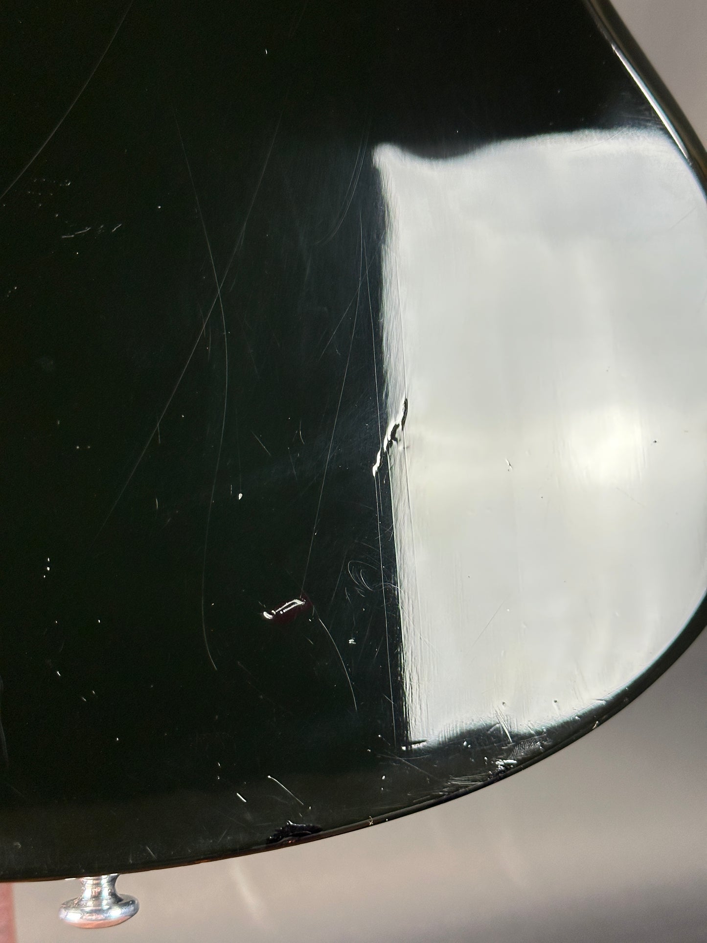 Close-up of a black car fender with a small dent and scratch.