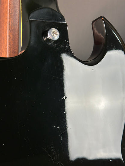 Close-up of a guitar's headstock with a screw and black finish.