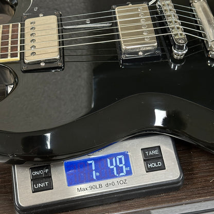 Black electric guitar on a digital scale displaying weight