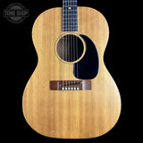 A vintage acoustic guitar with a natural wood body, black pickguard, and dark fretboard, shown against a solid black background. A 'TONE SHOP' watermark is visible in the top left corner.