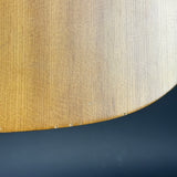 Close-up of a curved wooden surface with a warm honey-brown wood grain, meeting a dark navy blue background.