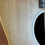 Close-up of an acoustic guitar's wooden body showing the natural wood grain, part of the sound hole, and a portion of the neck.