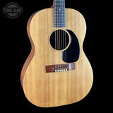 A vintage acoustic guitar with a natural wood body and a black pickguard, shown against a solid black background with a Tone Shop watermark in the top left corner.
