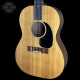 A vintage acoustic guitar with a natural wood body and dark sides, shown against a solid black background. A Tone Shop watermark is visible in the top left corner.