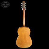 The back of a wooden acoustic guitar, showing the natural wood backplate and neck, photographed against a solid black background with a Tone Shop watermark in the top-left corner.