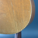 Close-up of a wooden acoustic guitar body showing the wood grain, finish, and edge damage against a blue background.