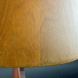 Close-up of a warm medium-brown wooden surface with visible wood grain and a small portion of a matching wooden support below.