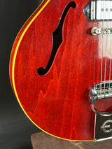 Close-up of a red electric guitar with a visible brand logo on a dark background