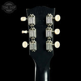 Close-up of a guitar headstock with tuning pegs on a black background, featuring the Tone Shop logo.