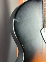 Close-up of a guitar's body with a focus on the black finish and wood grain.