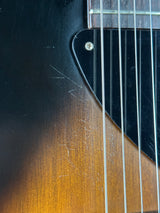 Close-up of a guitar's neck and fretboard with visible wear.