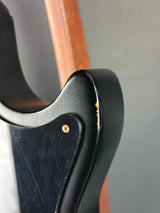 Close-up of a black leather belt with metal buckle on a wooden surface.