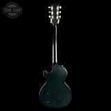 Back view of a black electric guitar with 'Tone Shop' logo.