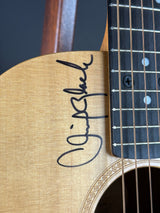Close-up of a guitar with a signature on the headstock