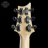 Close-up of a guitar headstock with tuning pegs on a black background, featuring the Tone Shop logo.