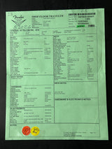 A light green paper work sheet or label with printed tables, barcodes, and text, photographed flat against a dark background. The sheet includes a header reading 'SHOP FLOOR TRAVELER' and a large 'Fender' logo at the top left.