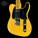 A yellow-finish electric guitar with a black pickguard and chrome hardware, shown against a black background with a Tone Shop watermark in the top left corner.