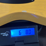A close-up of a yellow wooden guitar body resting on a black digital scale displaying 6 lbs and 8.0 oz.