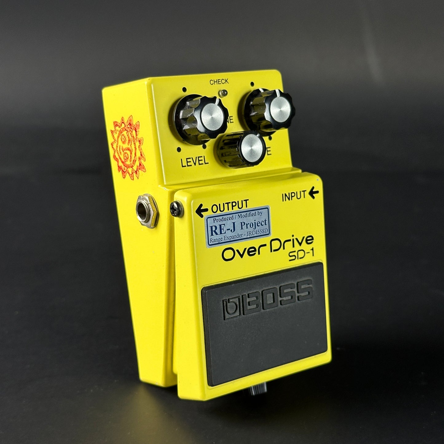 Yellow guitar effects pedal with 'Boss' branding on a dark background