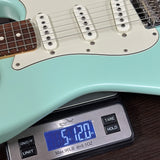 Light blue electric guitar on a digital scale displaying weight.