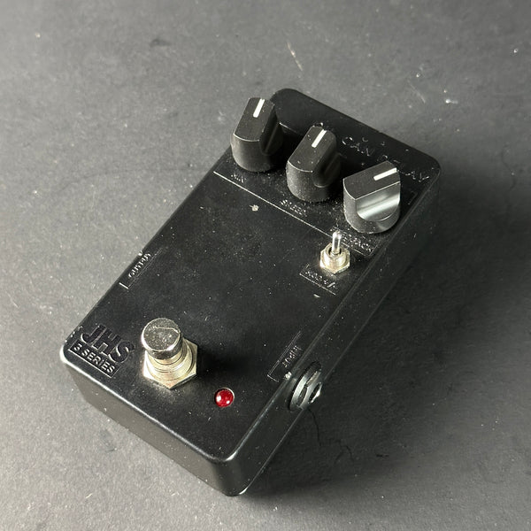 Black guitar effects pedal with knobs and switch on a gray surface