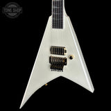 A white electric guitar with a distinctive angular body, black pickups, and gold hardware, shown against a solid black background. A 'TONE SHOP' watermark is visible in the top-left corner.