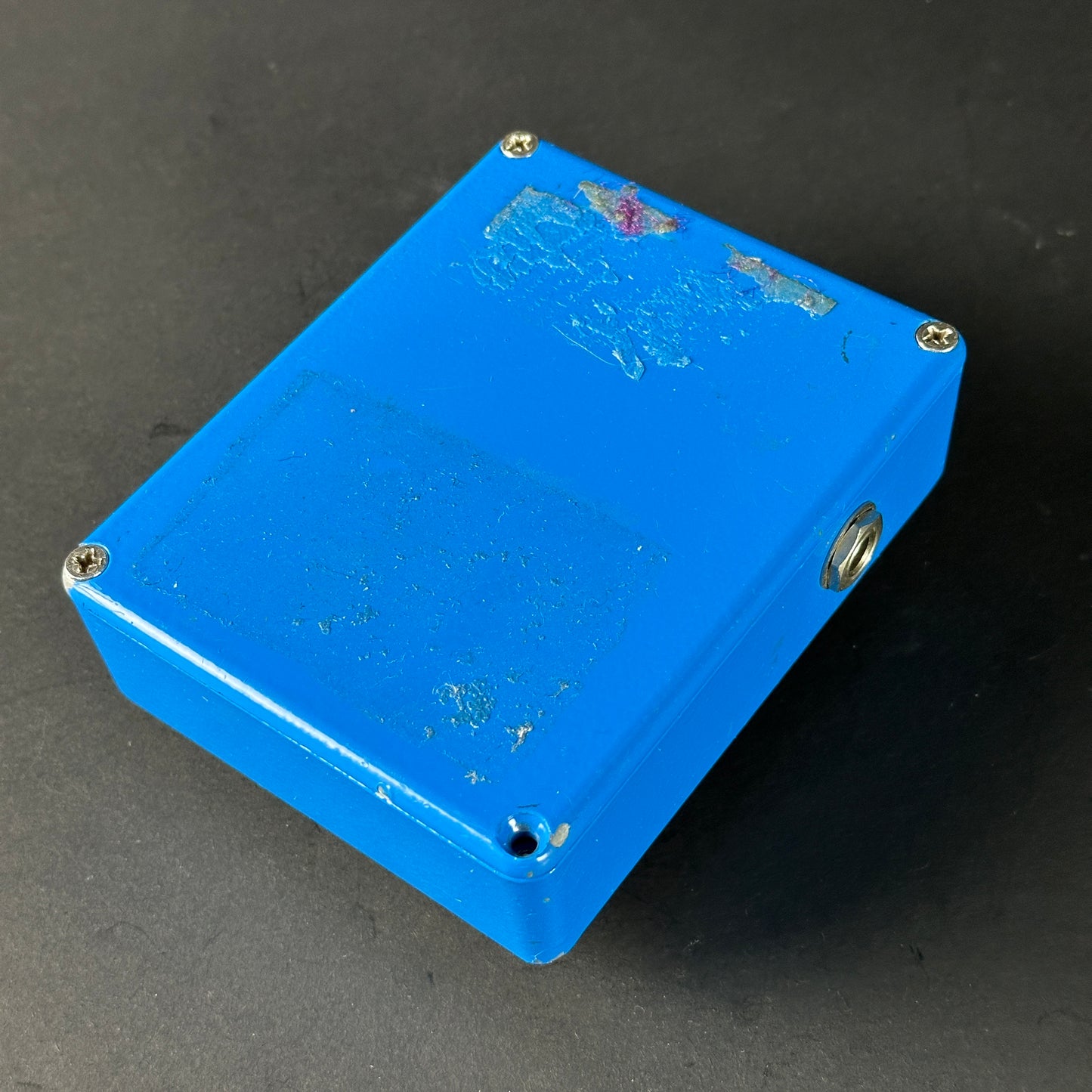 Blue rectangular box with screws on a dark gray background