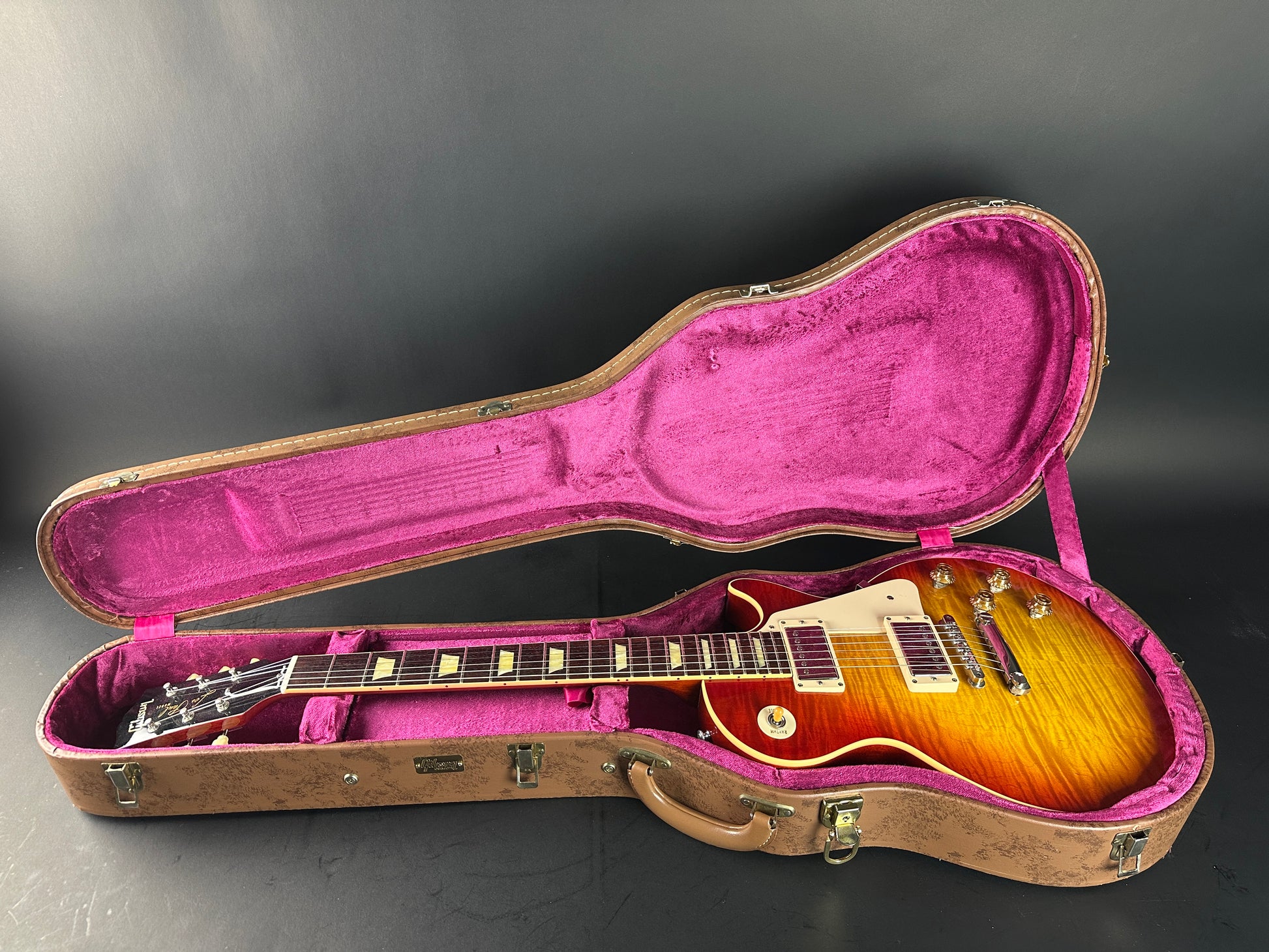 Open guitar case with a guitar inside on a dark background