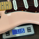 Guitar being weighed on a digital scale with a display showing weight.